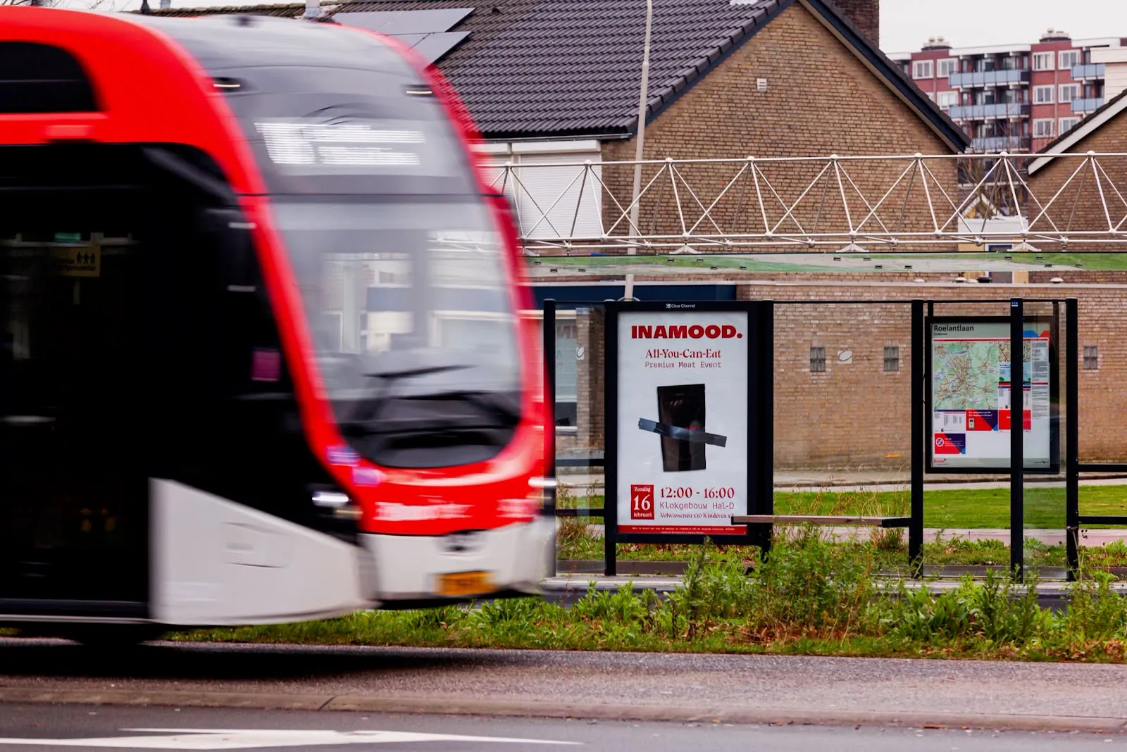 INAMOOD abri poster at a tram stop as a red tram passes