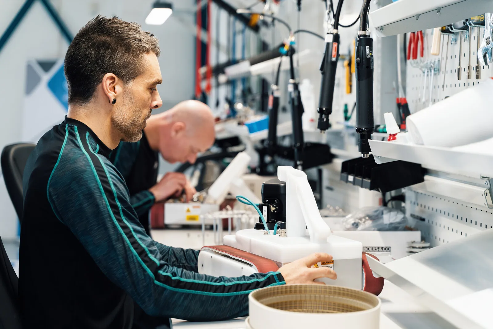 Two engineers working on a unit at the bench together