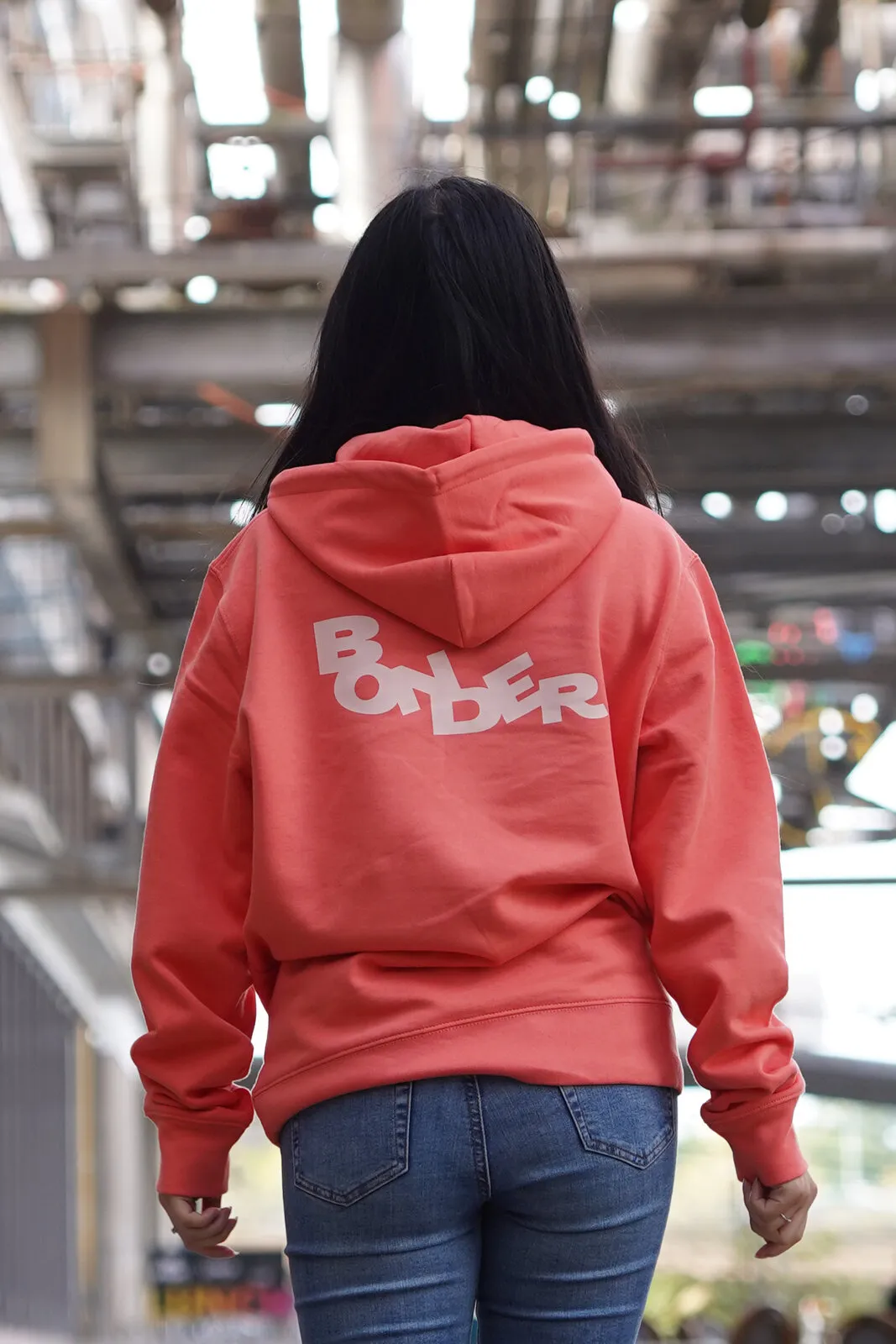 De koraalrode Bonder-hoodie van achteren, met het logo groot op de rug