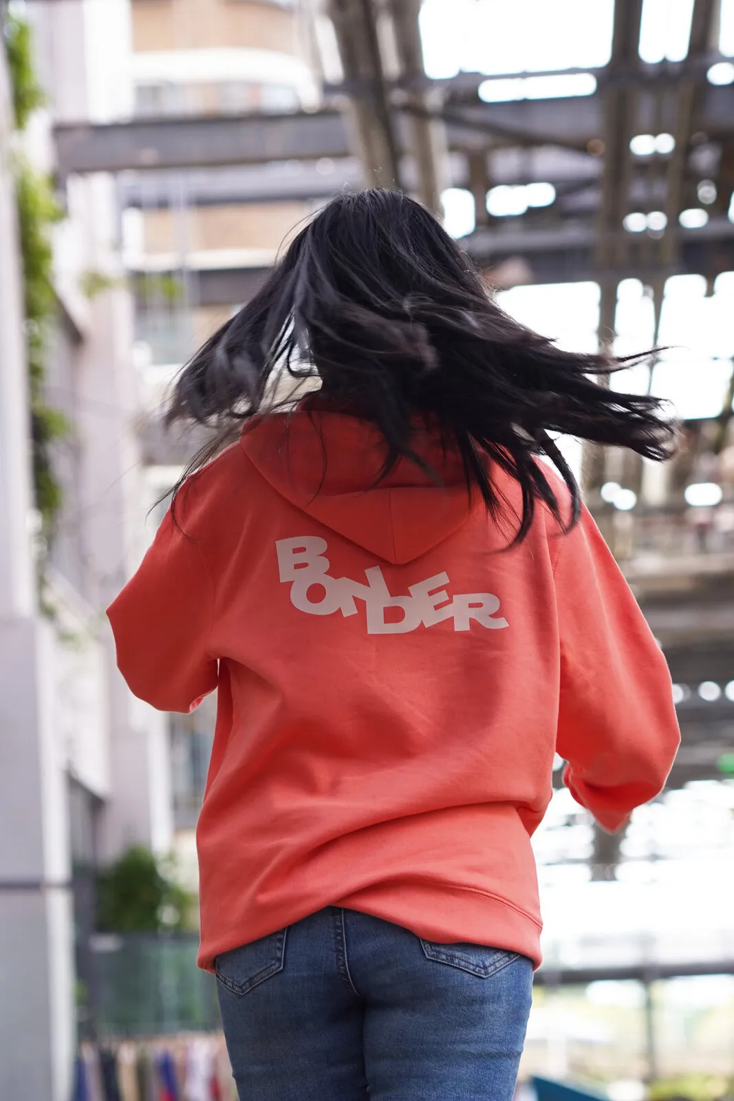 Een draai in de koraalrode hoodie, het haar in beweging