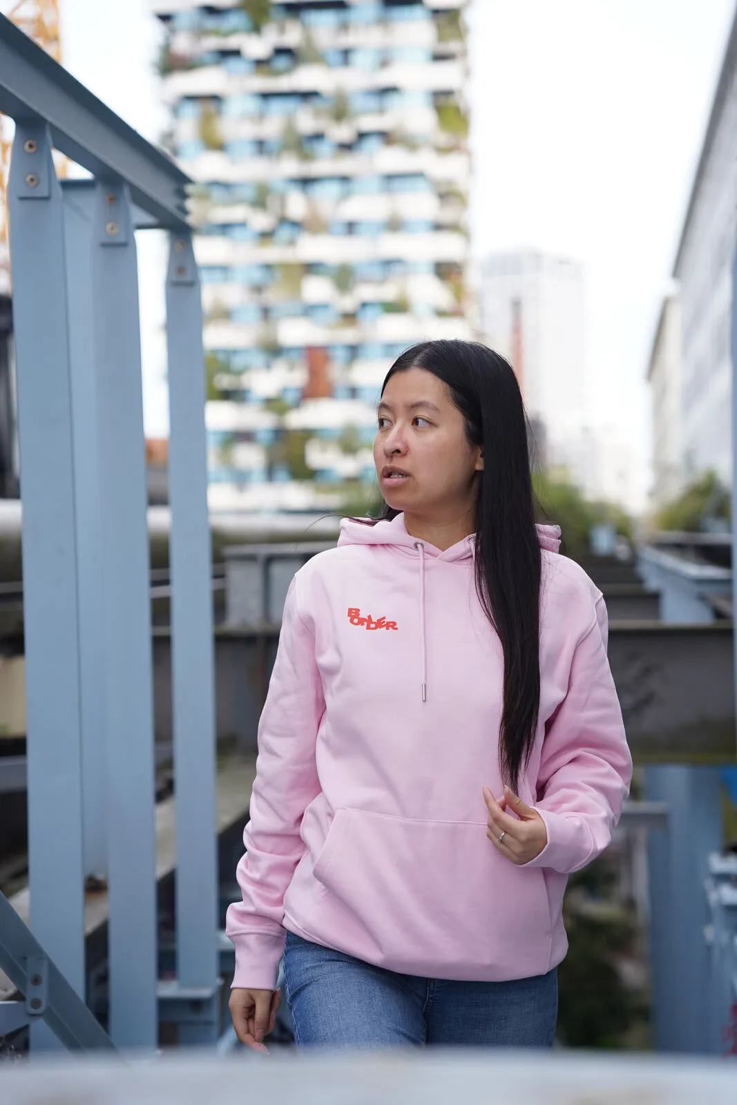 De roze Bonder-hoodie van voren, op een stalen loopbrug
