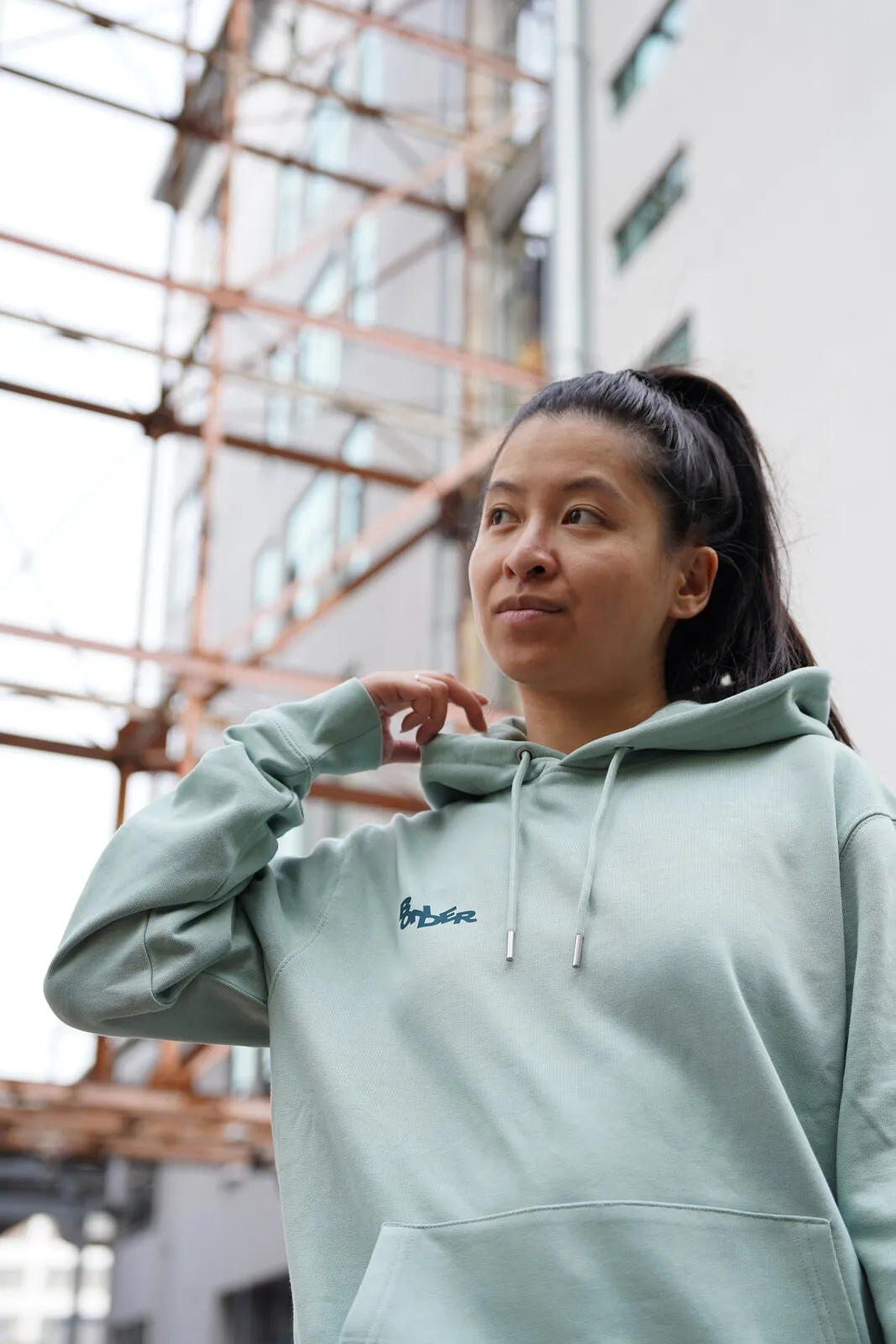De saliegroene hoodie van voren, voor een steiger