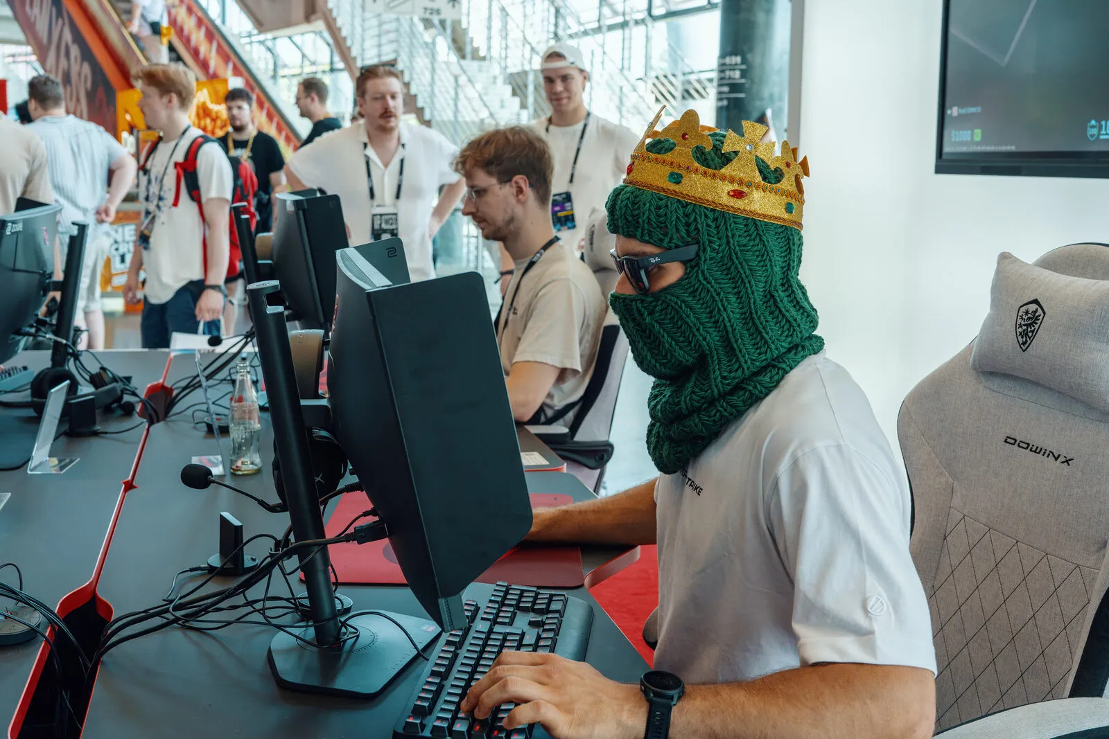 A visitor in a knitted crown playing the aim challenge, the queue waiting behind him