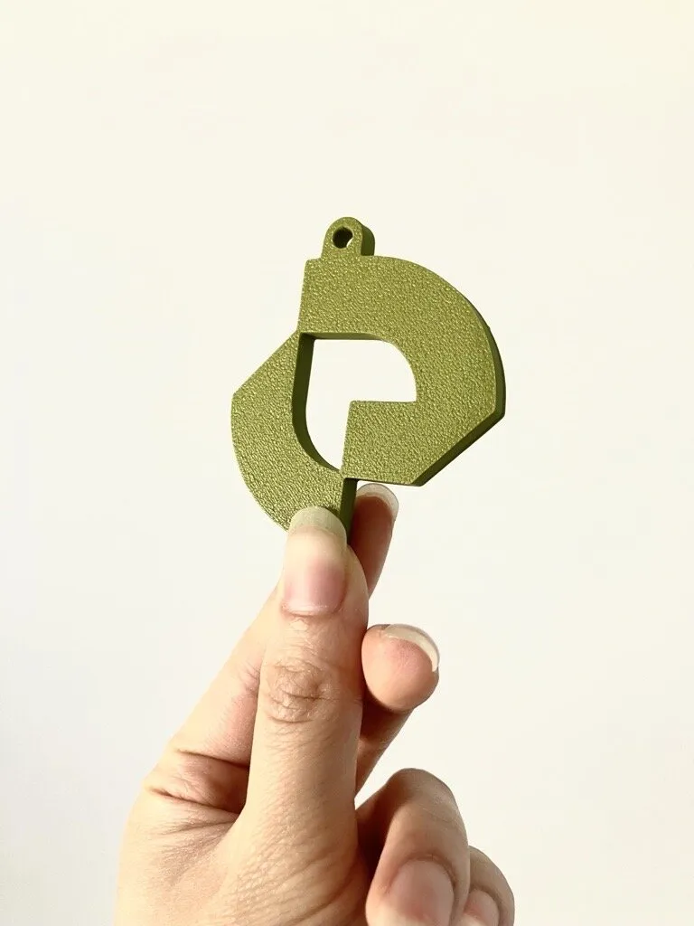 Een hand houdt de groene 3D-geprinte Exploitatie Partners-sleutelhanger vast