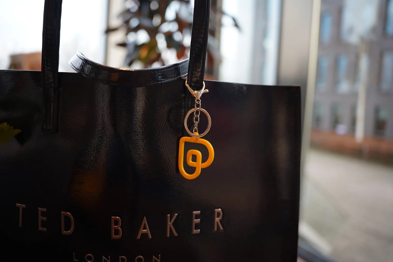 De gele sleutelhanger aan een zwarte tas