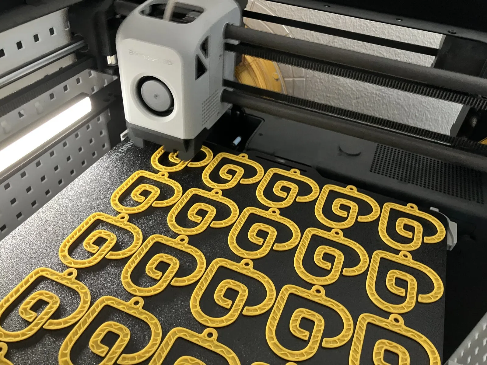 Een printbed vol gele Draaijer Heyday-sleutelhangers, net van de 3D-printer