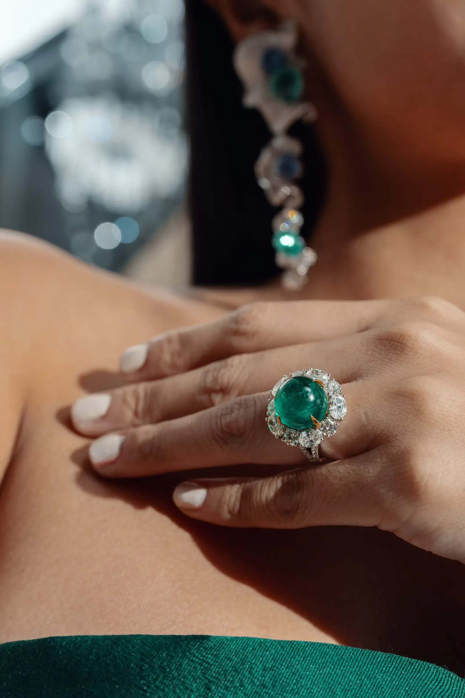 Cabochon emerald ring and matching drop earring, shot close on the hand