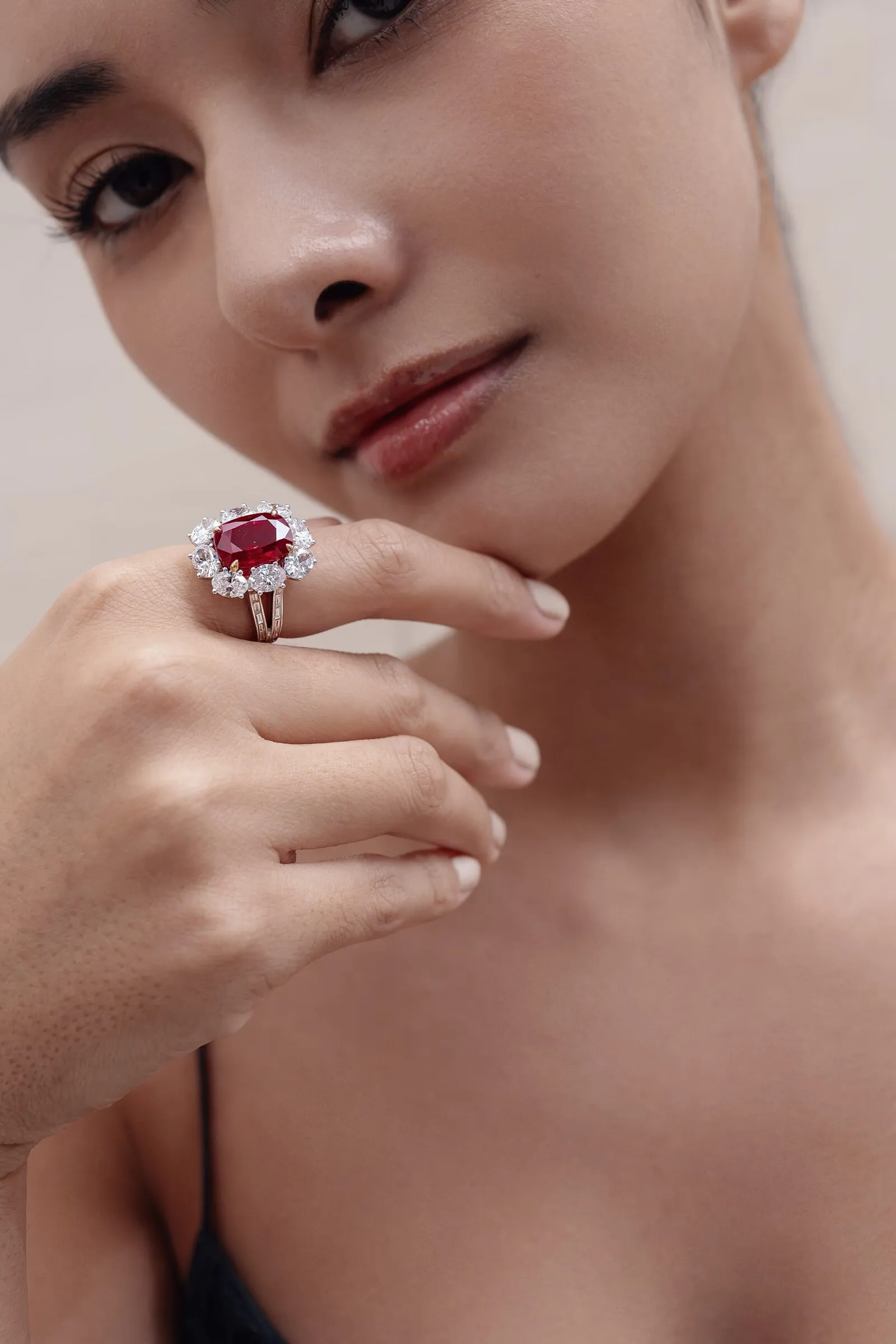 Cushion-cut ruby ring in a diamond cluster, held against the jaw