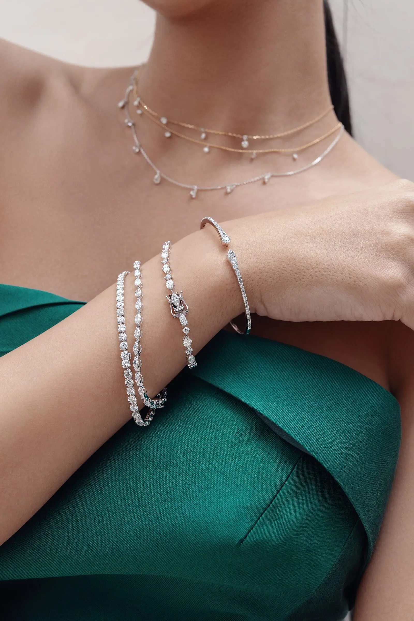 Three diamond bracelets and two layered diamond chokers worn together