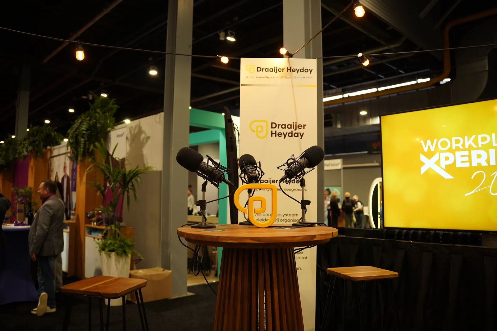 De podcasttafel op de stand van Draaijer Heyday, voor het gele Workplace Xperience-scherm