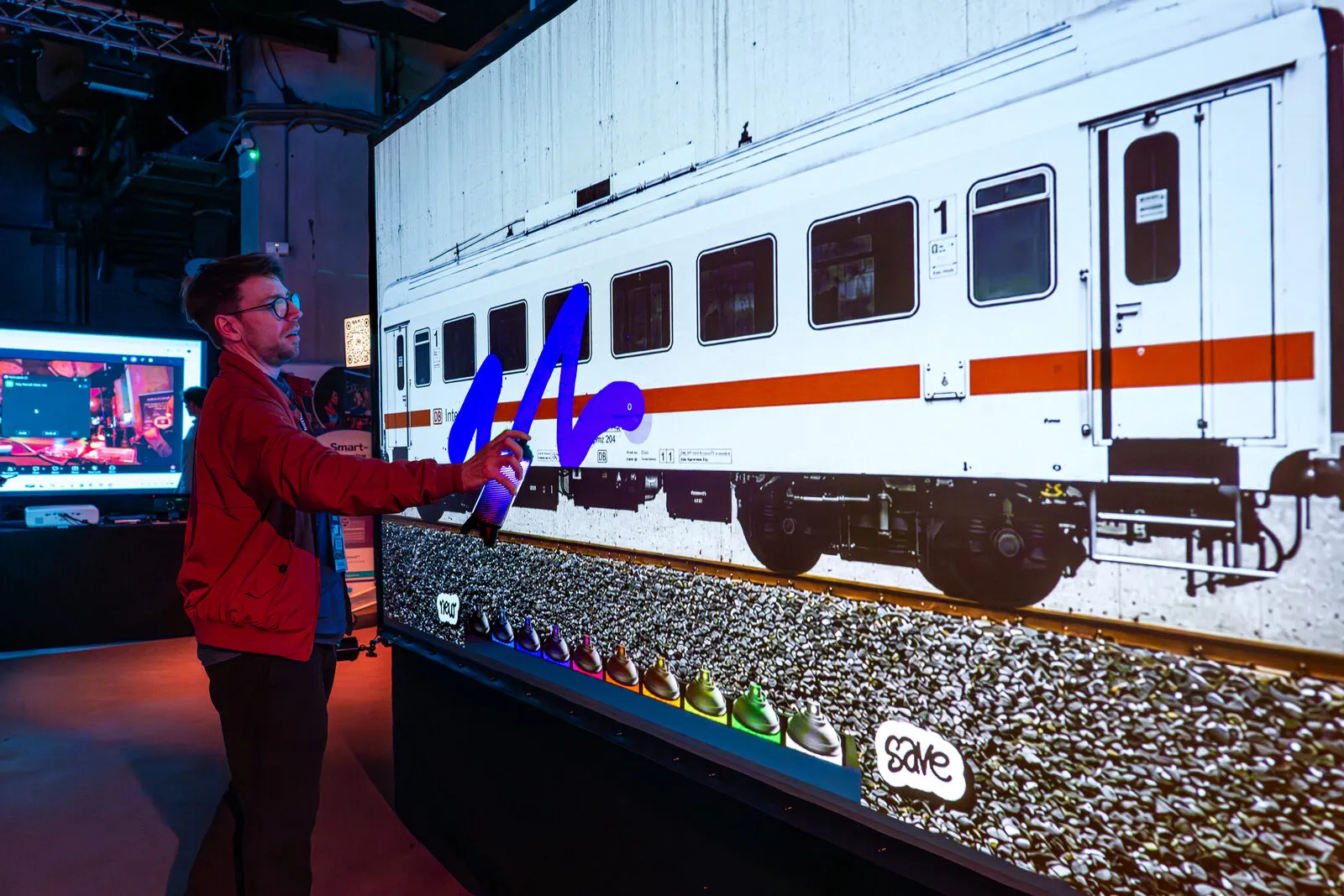 A guest painting a projected train carriage with a light spray can