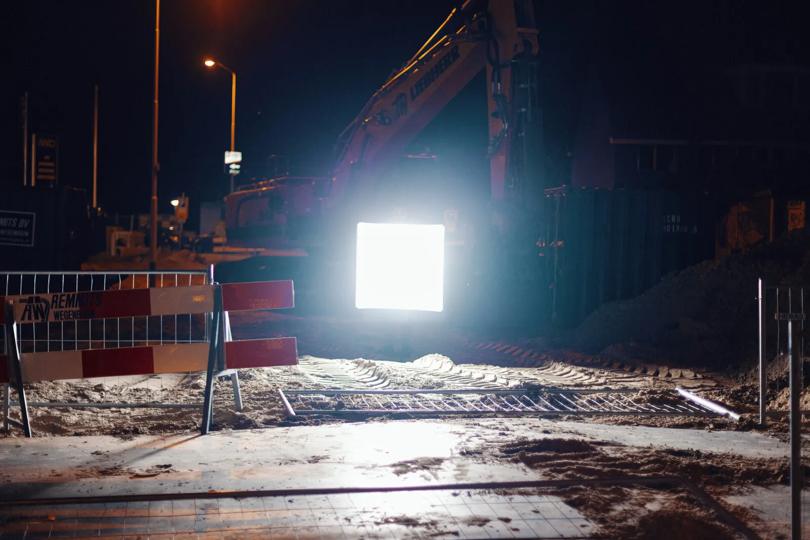 Het verlichte paneel tussen wegafzettingen, een graafmachine werkt erachter