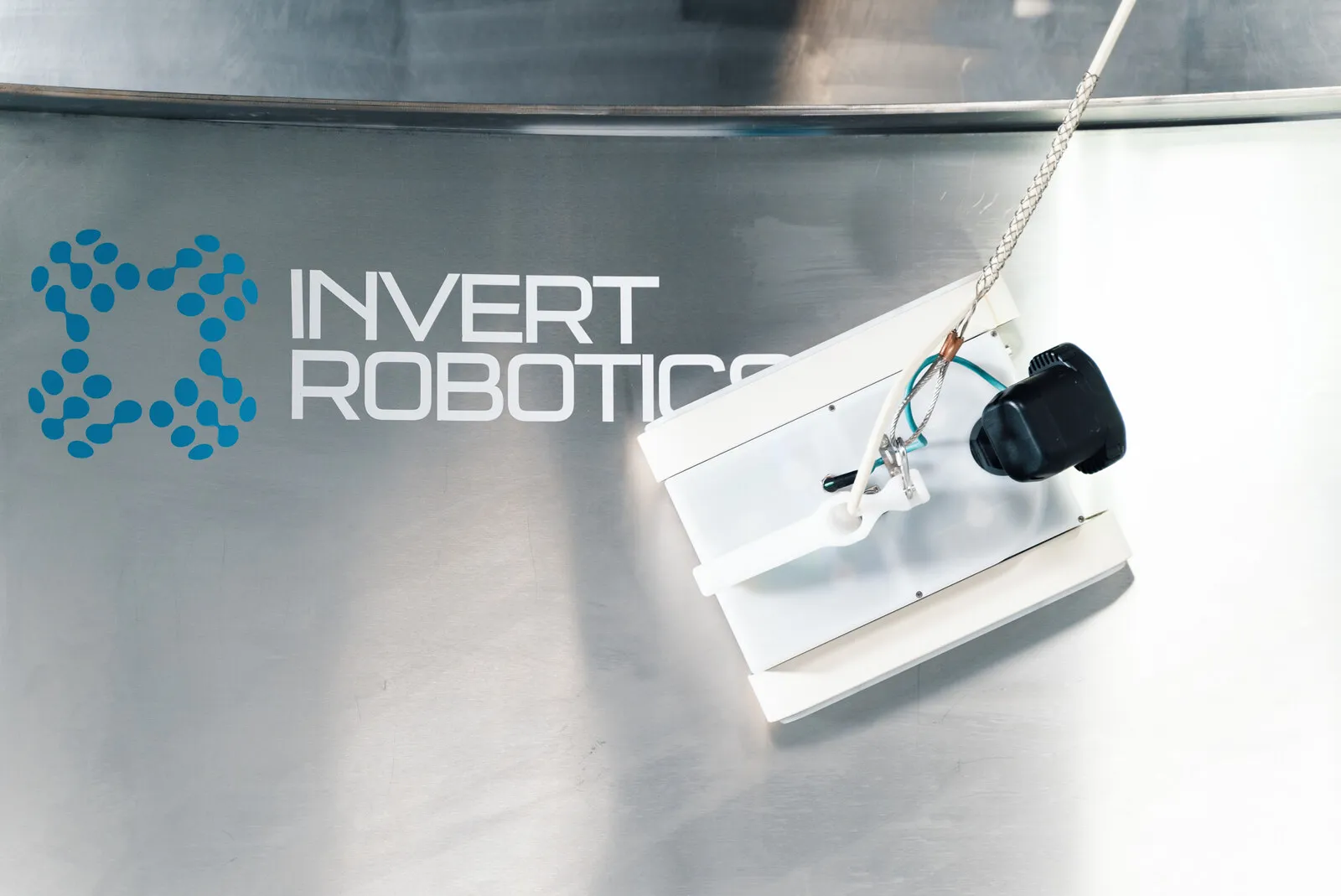 The crawler on a steel surface beside the Invert Robotics mark