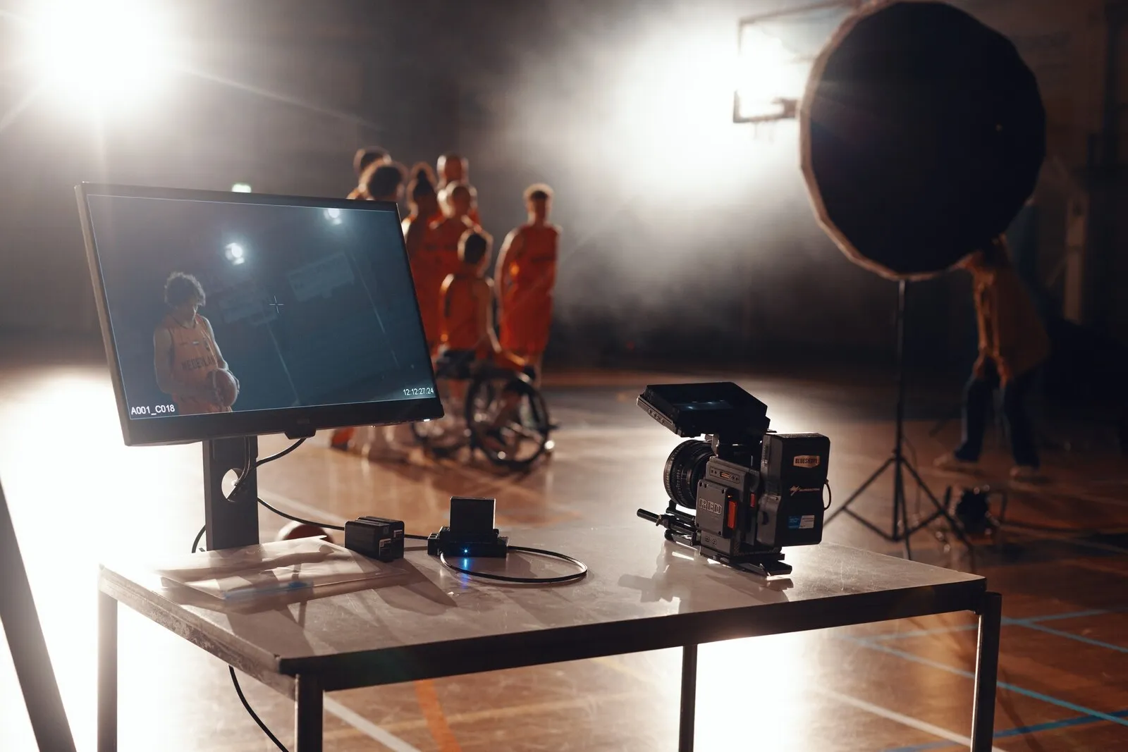 De monitor op tafel toont drie uitgelichte spelers op de vloer erachter