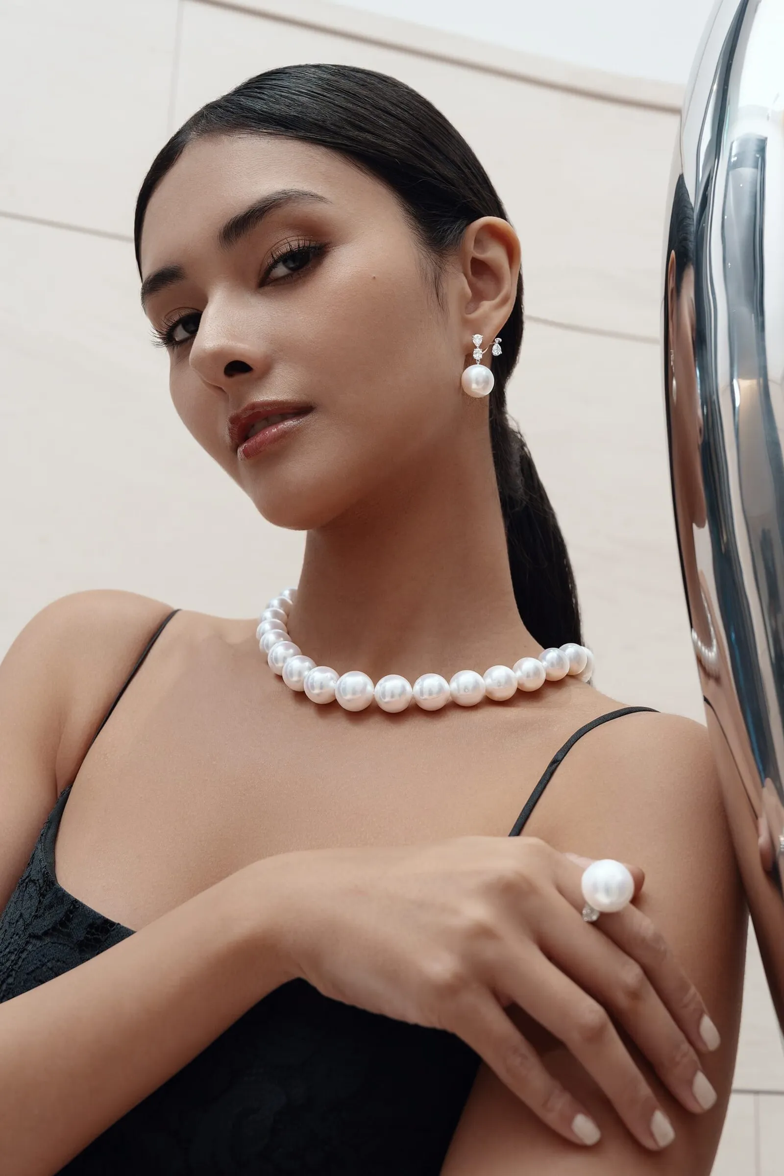 South Sea pearl necklace, earrings and ring, shot against a mirrored steel column