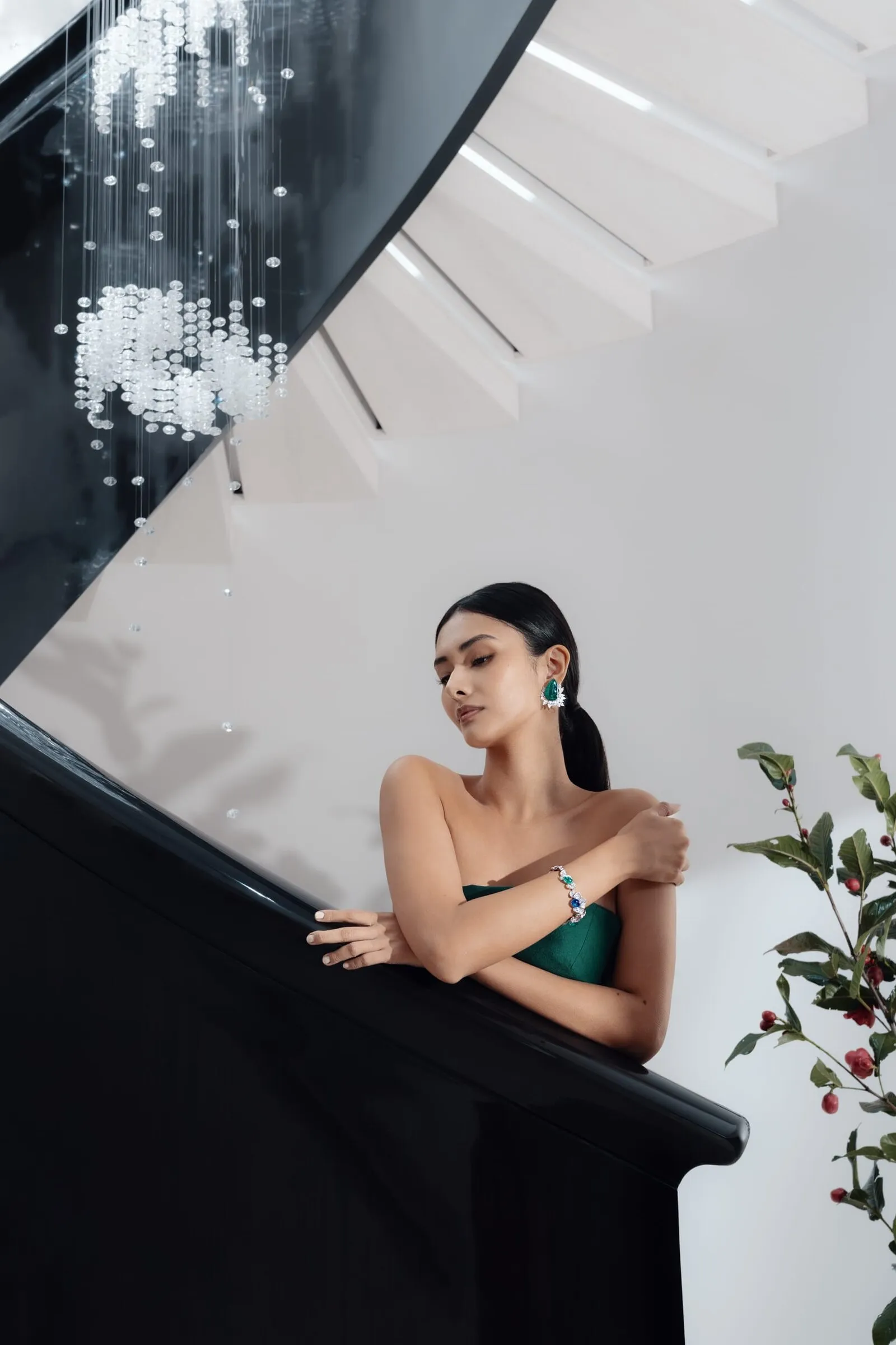 Model in a green gown on the store's spiral staircase under the crystal chandelier