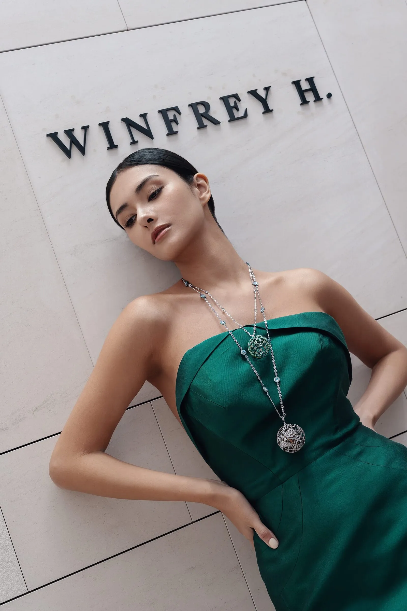Model in a green gown against the storefront wall, the Winfrey H. sign above her