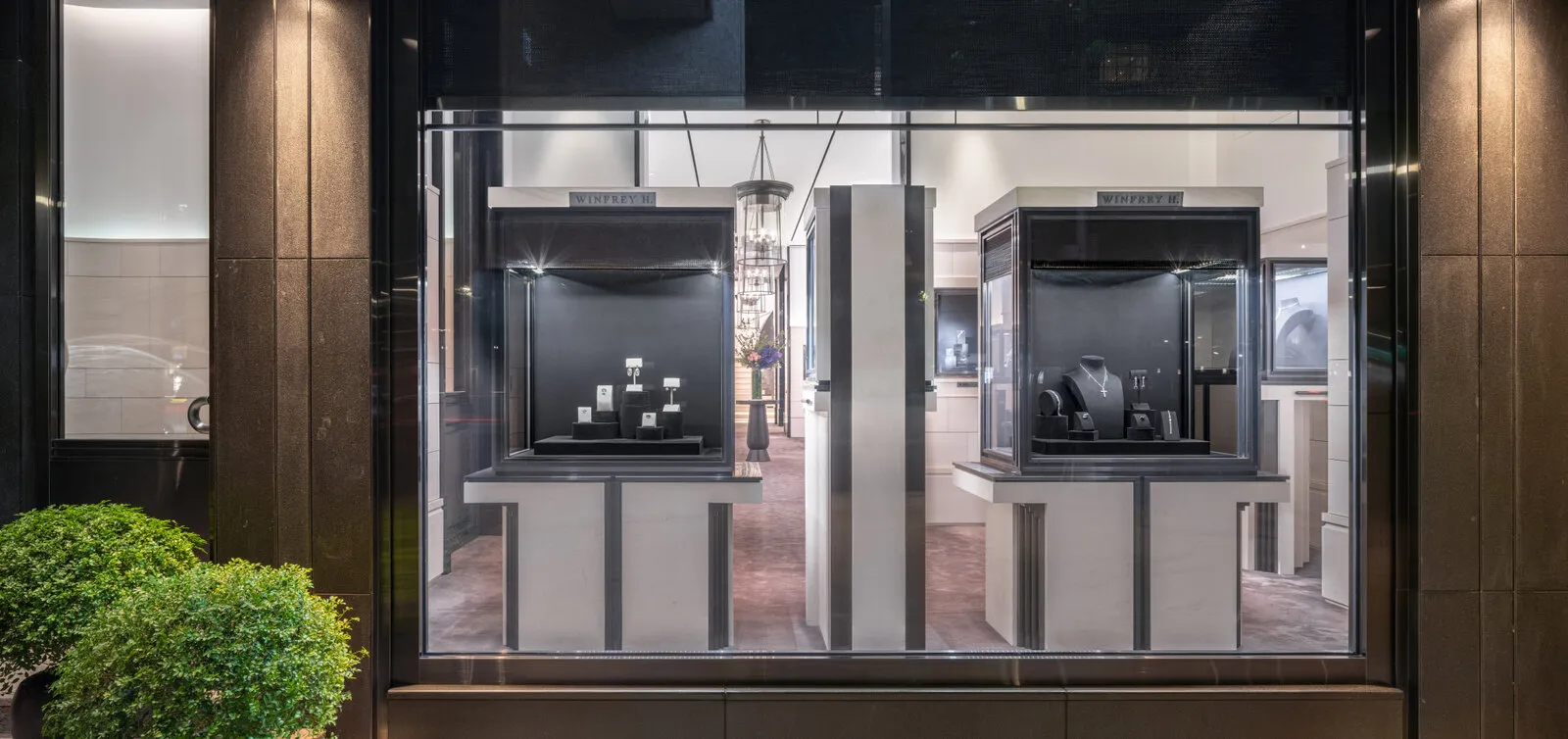 The lit shop window at night, two vitrines of jewelry behind the glass