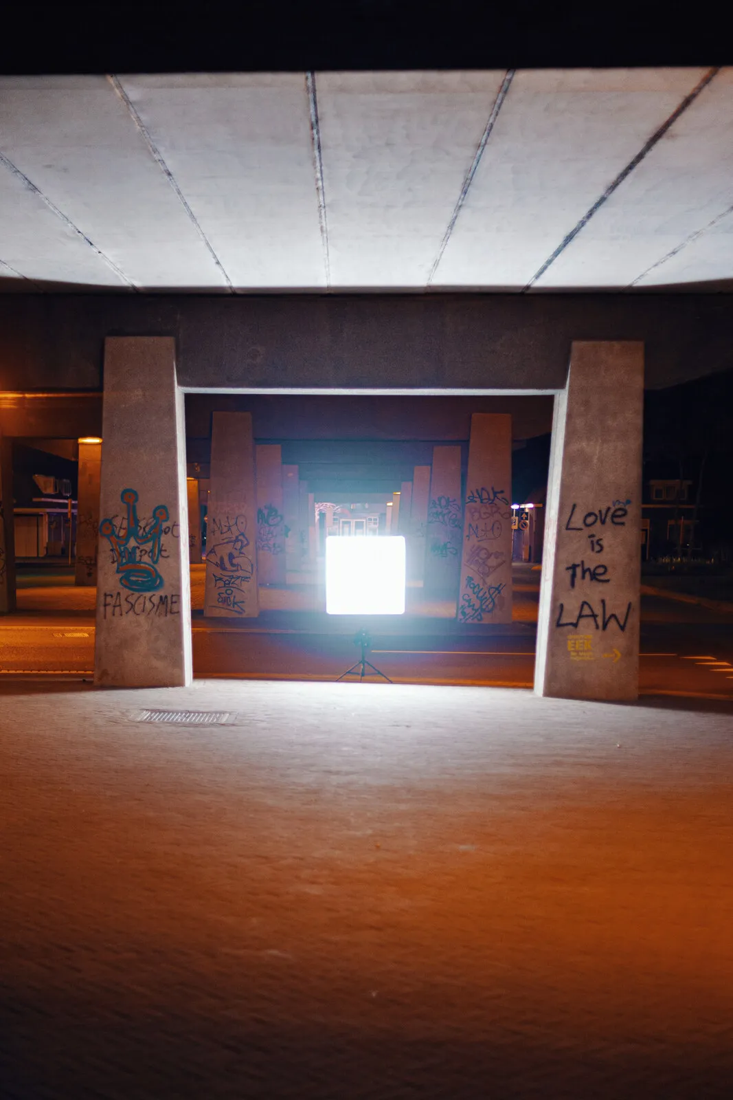 Het paneel alleen in een kale betonnen onderdoorgang, graffiti op de kolommen