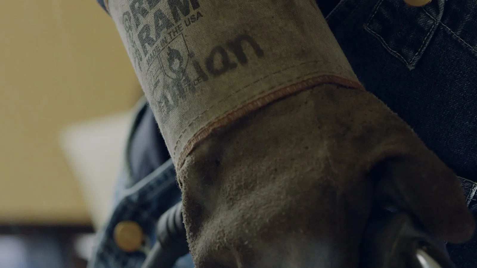 Een hand met handschoen aan de lasbrander, vonken van de naad